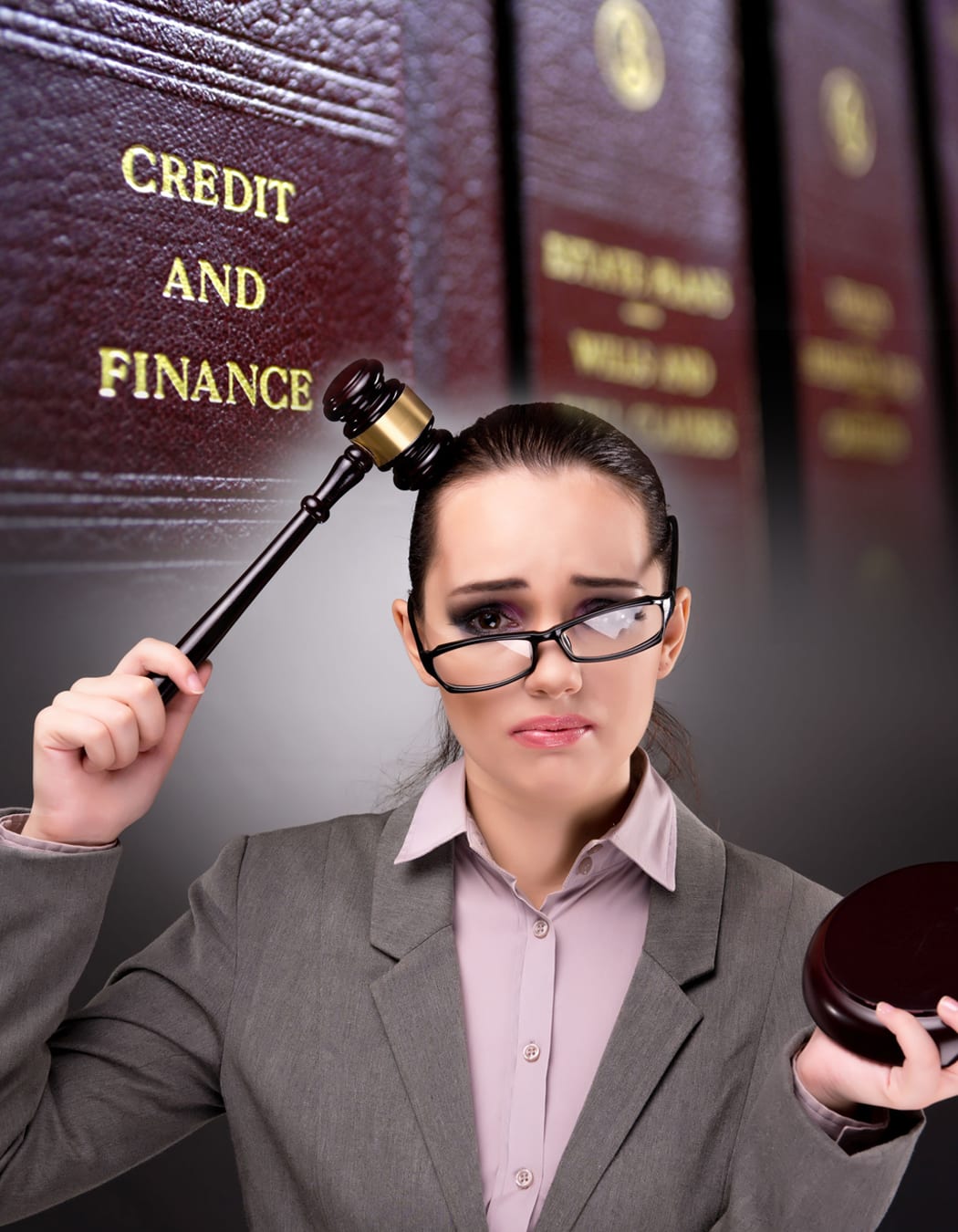 Humorous image of lawyer hitting herslef in head with gavel with Finance Law books in background