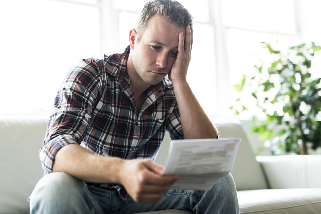 depressed man holding tax notice