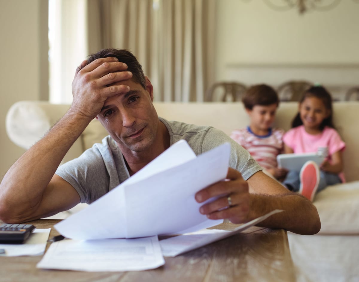 Father with tax problems looking at letter - his children are in background